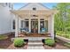 Inviting covered porch with comfortable seating, a ceiling fan, and stone steps amidst lush landscaping at 8901 Watkins Mill Rd, Winston, GA 30187