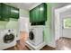 Well-lit laundry room featuring green cabinets, white appliances, and wood-look flooring at 1157 Alta Ne Ave, Atlanta, GA 30307