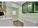 Well-lit laundry room featuring green cabinets, white appliances, and wood-look flooring at 1157 Alta Ne Ave, Atlanta, GA 30307