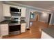 Kitchen boasts stainless steel appliances, white cabinets, and open layout to living area with beautiful hardwood flooring at 25 Stonehedge Dr, Buford, GA 30518