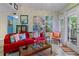 Cozy living room with a comfortable red couch, artistic wall decor, and inviting natural light through sheer curtains at 690 Mcgill Ne Pl, Atlanta, GA 30312
