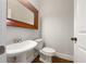 Compact powder room featuring a pedestal sink, cherry framed mirror, and a toilet at 2419 Boulder Se Rd, Atlanta, GA 30316