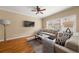 Bright living room with ceiling fan, hardwood floors, large windows, and neutral colored sofas and a television at 59 Townview Dr, Alpharetta, GA 30022
