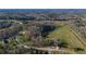 Expansive aerial view of the property, with mature trees, a large grassy field, and a winding driveway at 3721 Mason Creek Rd, Winston, GA 30187