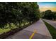 Tree-lined walking path with a yellow center line, adjacent to a road and green space at sunset at 388 Londonberry Road, Sandy Springs, GA 30327