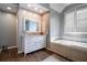 Elegant bathroom with a soaking tub, white vanity with marble countertop, and wood-look tile flooring at 3220 Millwood Se Trl, Smyrna, GA 30080