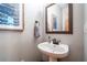 Elegant powder room featuring a pedestal sink, decorative mirror, and stylish blue-themed artwork at 3220 Millwood Se Trl, Smyrna, GA 30080