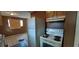 Dilapidated kitchen featuring white appliances, upper cabinets and stained tile floors at 45 James P Brawley Nw Dr, Atlanta, GA 30314