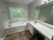 Bright bathroom featuring a soaking tub with tile surround and a white vanity with a mirror at 4911 Hairston Pl, Stone Mountain, GA 30088