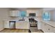 Modern kitchen featuring stainless steel appliances, white cabinetry, and wood-look floors at 5368 Knights Lndg, Ellenwood, GA 30294