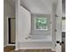 Serene main bathroom featuring a soaking tub, a window for natural light, and wood-look flooring at 5368 Knights Lndg, Ellenwood, GA 30294