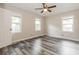 Bright bedroom featuring grey wood-look floors, a ceiling fan, and two large windows for natural lighting at 823 Catherine St, Forest Park, GA 30297