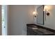 Bathroom vanity with black countertop and a mirror with sconces lighting at 10765 Shallowford Rd, Roswell, GA 30075