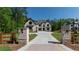 A grand driveway entrance with brick pillars, manicured lawns, and a view of the home at 10765 Shallowford Rd, Roswell, GA 30075