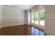 Bright, empty room with large windows and rich hardwood floors at 10765 Shallowford Rd, Roswell, GA 30075