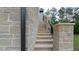 Stone steps lead to the upper level, complemented by a wrought iron railing and stone pillars at 10765 Shallowford Rd, Roswell, GA 30075