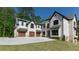 An exterior shot highlighting a home's garages, upper balcony, and well-maintained lawn at 10765 Shallowford Rd, Roswell, GA 30075