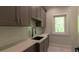 Kitchenette boasts gray cabinets, subway tile backsplash, quartz countertop, and a window overlooking the outdoors at 10765 Shallowford Rd, Roswell, GA 30075