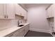 Well-appointed laundry room boasts a sleek sink, ample counter space, and plenty of custom cabinet storage at 10765 Shallowford Rd, Roswell, GA 30075