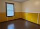 This bedroom has hard floors, a window with blinds, and yellow wood paneling on the bottom half of the walls at 1253 Todiway Ct, Jonesboro, GA 30238