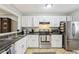 A bright kitchen featuring white cabinetry, stainless steel appliances, and ample countertop space at 4216 Stillwater Dr, Duluth, GA 30096