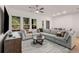 Spacious living room featuring a large sectional sofa, ceiling fan, and oversized windows overlooking mature trees at 1070 Harper Dr, Alpharetta, GA 30076