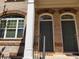 Charming brick townhome exterior featuring two front doors with arched entryways and classic architectural details at 10856 Ellicot Way, Alpharetta, GA 30022