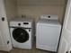 Bright laundry room with a modern, front-load Samsung washer and dryer set and wire shelving for storage at 10856 Ellicot Way, Alpharetta, GA 30022