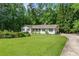Charming single-story home featuring a well-manicured lawn and a driveway surrounded by lush greenery at 1824 Mcclung Rd, Hiram, GA 30141