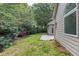 Side view of the backyard with a concrete patio next to the home and a wall of green trees at 3314 Dilmus Dr, Powder Springs, GA 30127