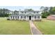 Inviting two-story home featuring a well-manicured lawn, mature trees, and charming architectural details at 100 Fairview Dr, Stockbridge, GA 30281