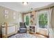 Bright Bedroom featuring a crib, comfortable gray rocking chair, and large windows with serene outdoor views at 2078 Marshalls Se Ln, Atlanta, GA 30316
