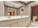 Bathroom with dual sinks, wallpaper, and an adjoining room reflected in the mirror at 4953 Mcpherson Ne Dr, Roswell, GA 30075