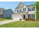 Charming two-story home with a white brick facade, attached garage, manicured lawn, and beautiful landscaping at 7455 Easton Valley Ln, Cumming, GA 30028