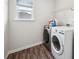 Well-lit laundry room featuring a modern washer and dryer, with wood-look flooring and functional shelving at 7455 Easton Valley Ln, Cumming, GA 30028