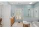 Bright bathroom featuring a soaking tub, walk-in shower, and vanity with natural wood cabinets at 6575 Eli Davis Rd, Cumming, GA 30040