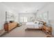 Bright main bedroom with neutral walls, wood furniture, carpet, and white bedding illuminated by a modern chandelier at 6575 Eli Davis Rd, Cumming, GA 30040