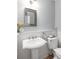 Charming powder room with a pedestal sink, decorative mirror, and wainscoting at 6575 Eli Davis Rd, Cumming, GA 30040