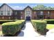 Brick apartment building showcasing landscaped bushes, a front walkway, and double door entry at 6851 Roswell Rd # H12, Atlanta, GA 30328