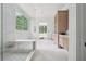 Bright bathroom showcasing a glass shower, natural wood vanity, and large window with green view at 1145 Kingston Drive, Atlanta, GA 30342