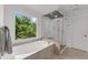 Modern bathroom featuring a glass shower, soaking tub, and a large picture window at 2135 Glenfield Trce, Cumming, GA 30041