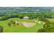 Scenic aerial view of a lush golf course with a clubhouse, pond, and surrounding greenery at 2135 Glenfield Trce, Cumming, GA 30041