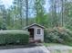 Small out-building is framed by green bushes and mature trees in a peaceful outdoor setting at 4445 Moon Station Nw Ln, Acworth, GA 30101