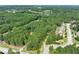 Expansive aerial view showcases the neighborhood, the surrounding lush greenery, and a serene lake in the distance at 558 Auburn Rd, Auburn, GA 30011