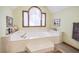 Luxurious bathtub features a marble surround, arched window, and elegant fixtures at 558 Auburn Rd, Auburn, GA 30011