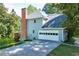 Side exterior showcasing attached garage, driveway, brick chimney, and backyard access at 558 Auburn Rd, Auburn, GA 30011