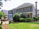 Rear exterior featuring a stone patio, manicured lawn, and abundant landscaping at 2308 Littlebrooke Dr, Dunwoody, GA 30338