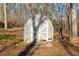 Barn style storage shed with aged gray siding, white doors, and surrounded by a wooded lot at 405 Miller Rd, Covington, GA 30014