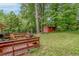 Large backyard with a wooden deck, lush grass, and a small storage shed surrounded by trees at 1145 Arbordale Dr, Decatur, GA 30033