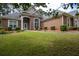 Charming brick home featuring a well-manicured lawn, arched entryway, and lush landscaping at 240 Huiet Dr, Mcdonough, GA 30252
